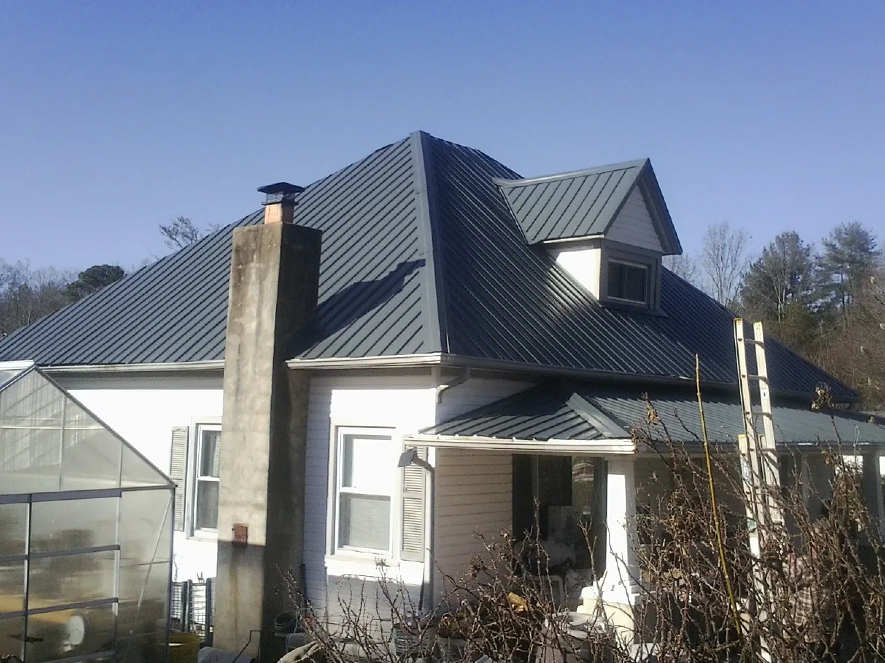 Dark blue standing seam metal roof on a white farmhouse with dormer — Slate & Tile Roof Repair by Roofing Brothers in Gibbstown