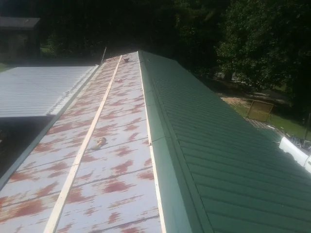 Old rusted panels beside newly installed green metal roofing — Wind Damage Roof Repair by Roofing Brothers in Gibbstown
