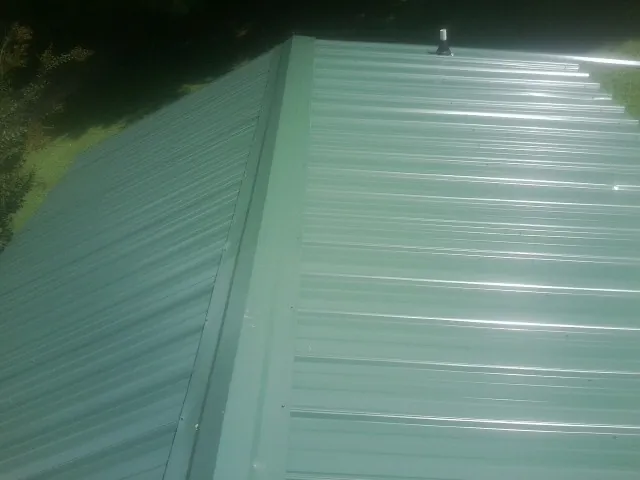 New green metal panels meeting at the ridge of a roof — Flat Roof Repair work by our crew in Gibbstown