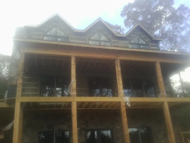 Dormers and porch framing on a large log home under construction — Roof Coating work by our crew in Gibbstown