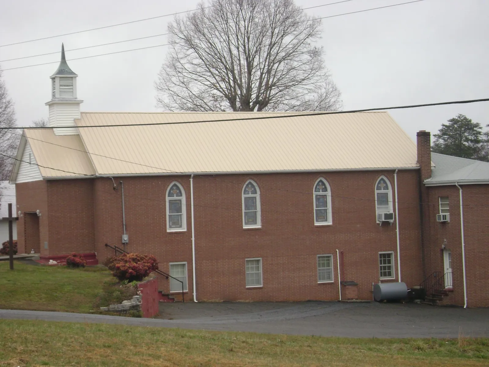 New tan metal roof on a brick church with a white steeple in Gibbstown