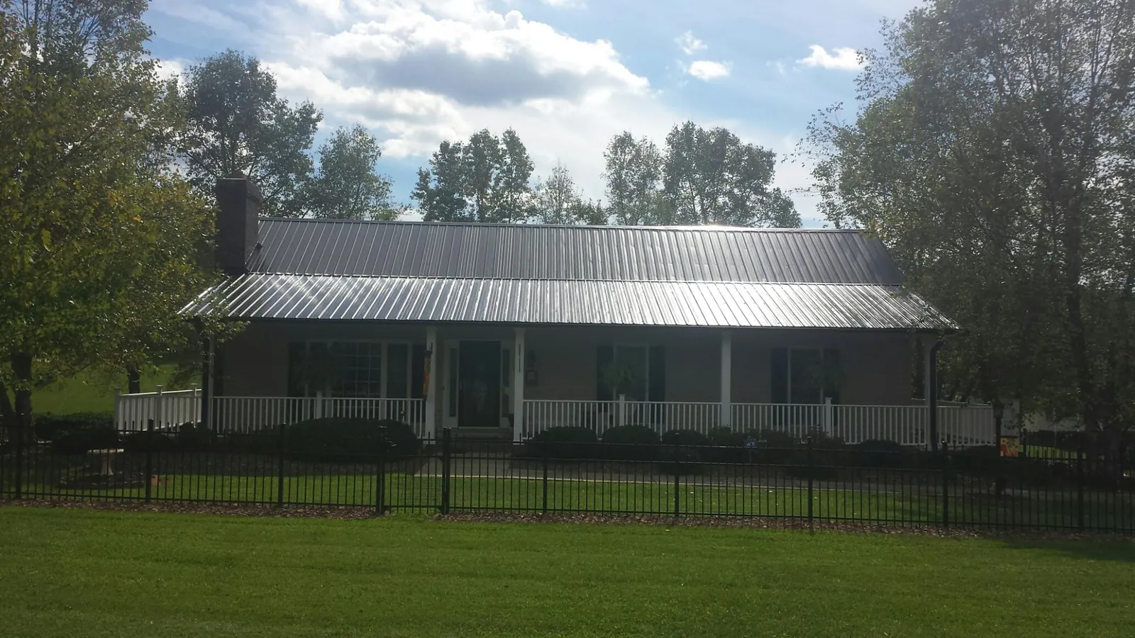 Gray metal roof on a brick ranch with a full width front porch — Gutter Guard Installation work by our crew in Gibbstown