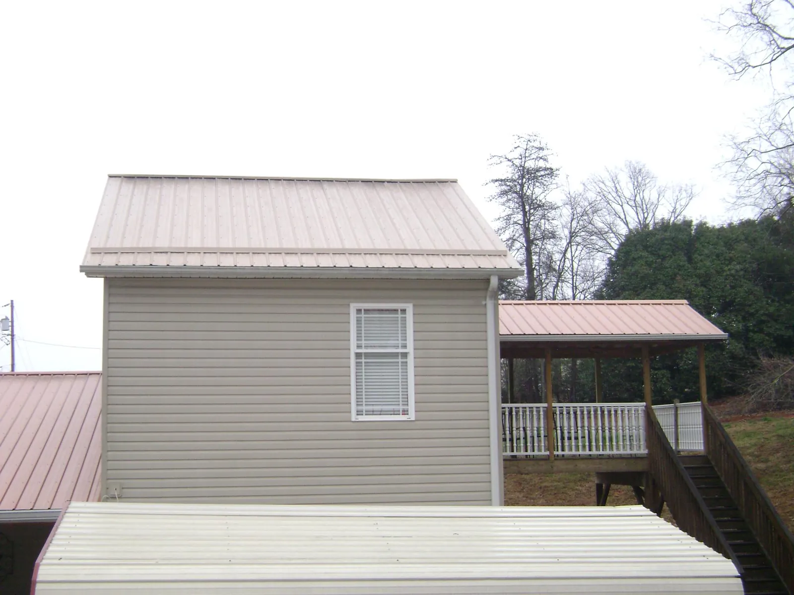 Tan metal roofs on a two story addition and attached porch, from a Roof Replacement job in Gibbstown