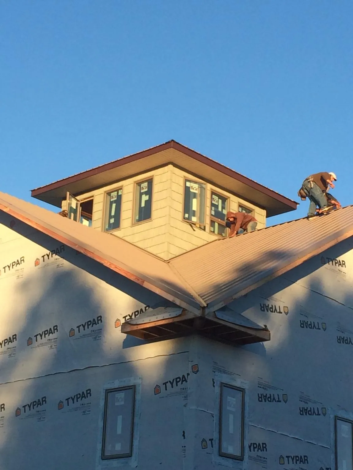 Roofers working around a rooftop cupola on a new metal roof at sunset — Roof Waterproofing in Gibbstown by Roofing Brothers
